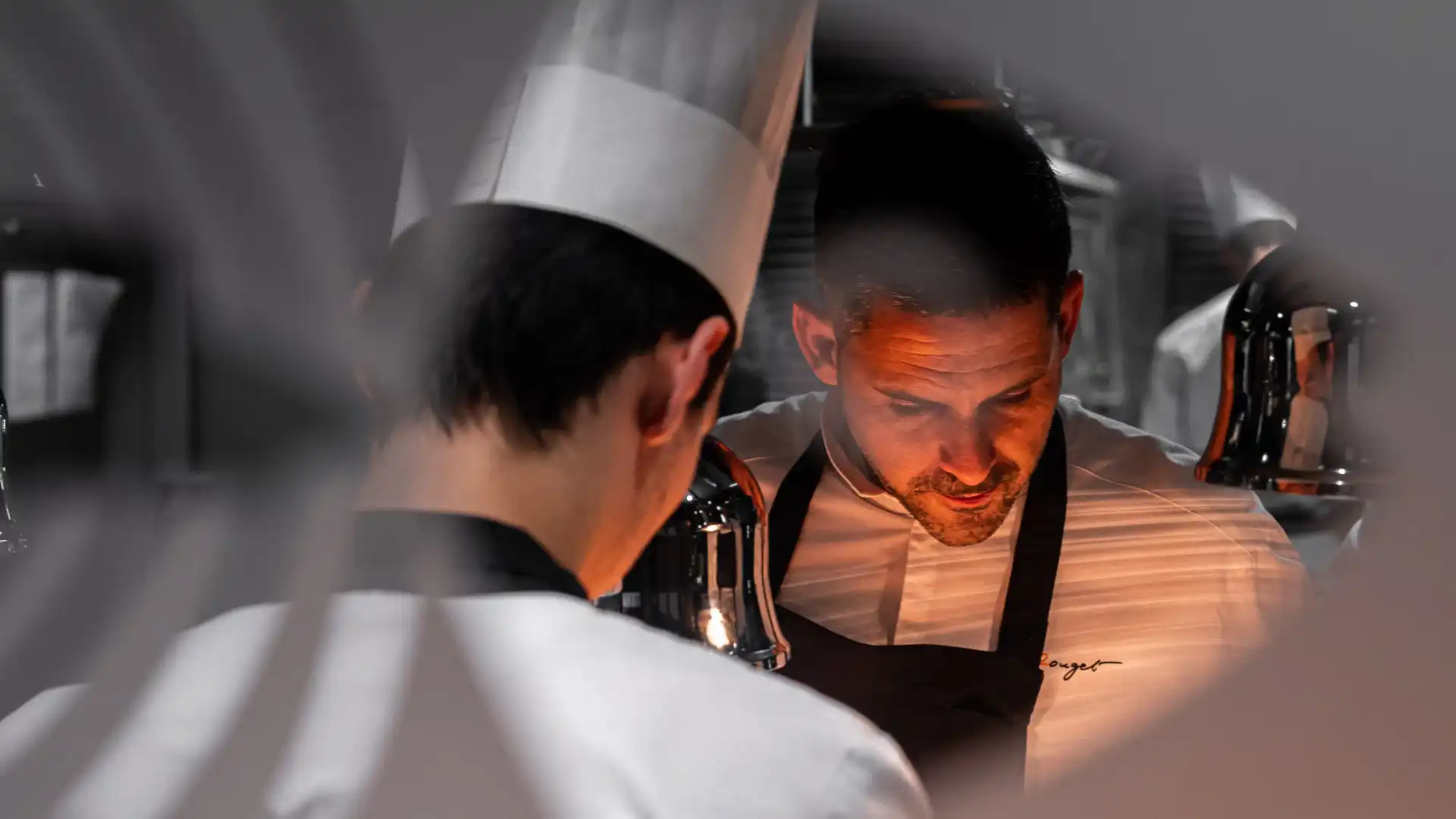 Deux personnes en tenue de cuisine discutent dans un environnement professionnel